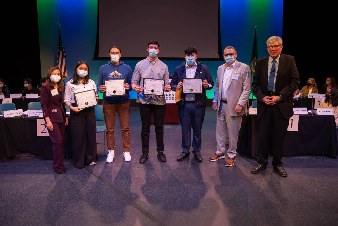 Group poses in Black Box Theatre with certificates of participation