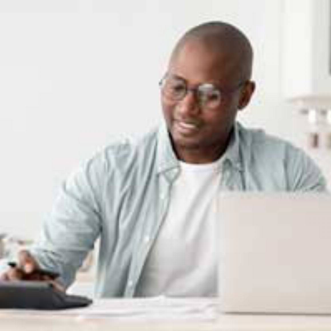 man using a calculator and laptop