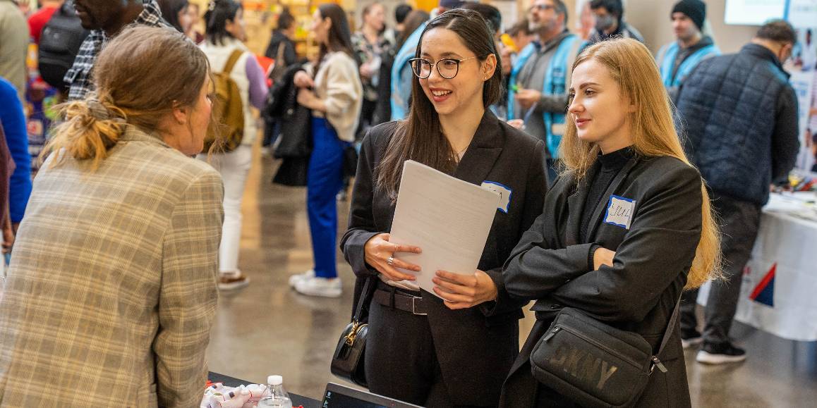 Two students at a table talking to a counselor.