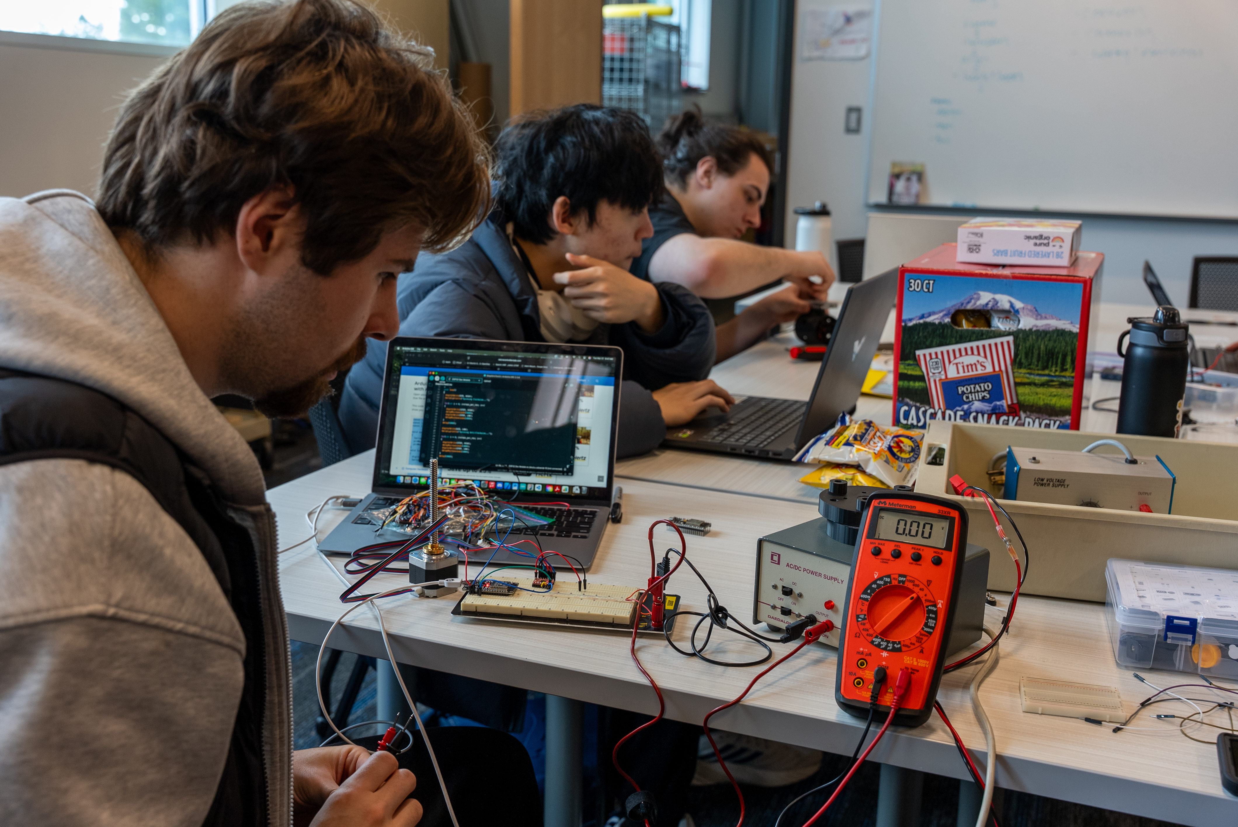Three students sitting at a table working on various tasks to build their ROV model. (Photo by Miranda Shook).