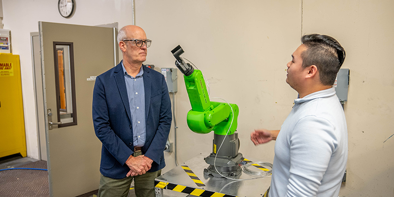 Representative Larsen and manufacturing faculty and discusing the robot arm at the AMSC center. Representative Larsen and manufacturing faculty and discusing the robot arm at the AMSC center.