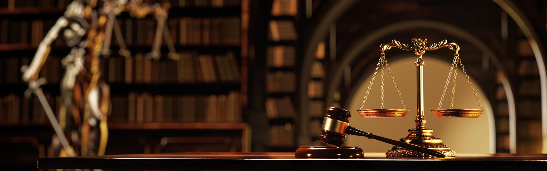 scales of justice on a table with books in a library in the background