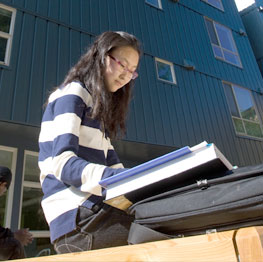 Woman reading a textbook outside of the dormatory