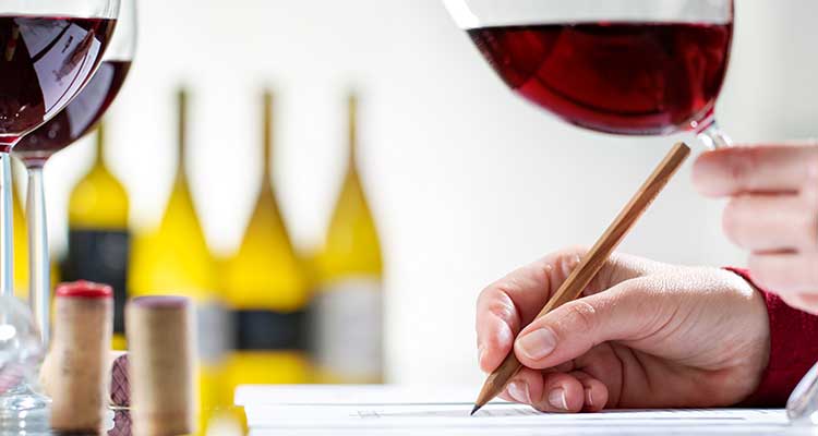 man holding a wine glass and writing