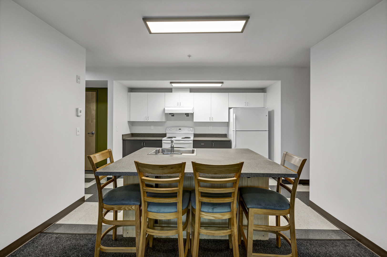 itchen with large island and four wooden bar stools, white cabinets, and full appliance set