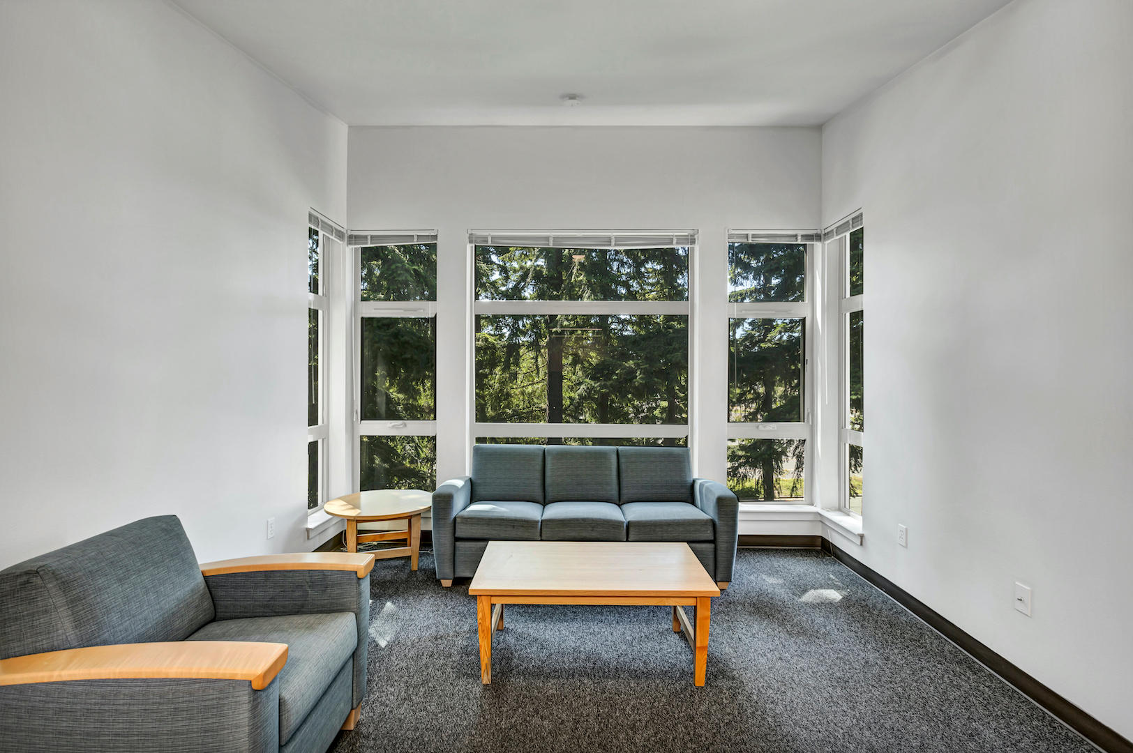 Wide view of living room with seating arrangement and expansive windows providing natural light.