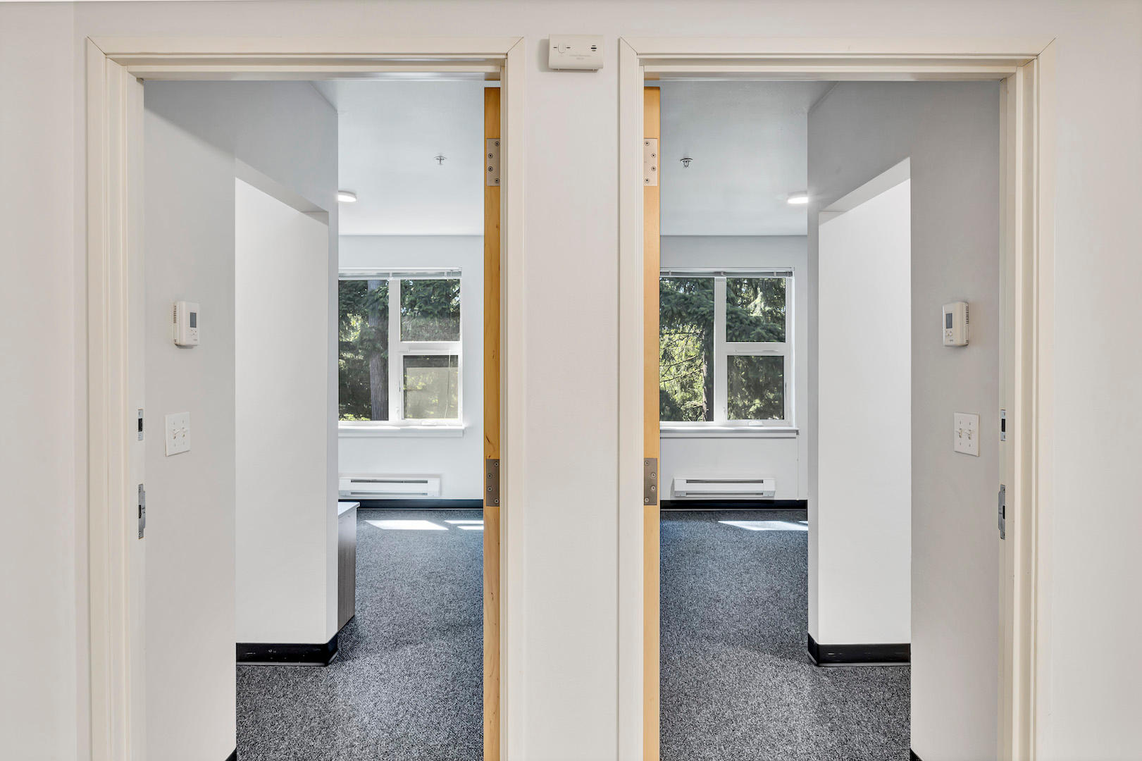 View through two adjacent doorways leading into bedrooms with windows visible.