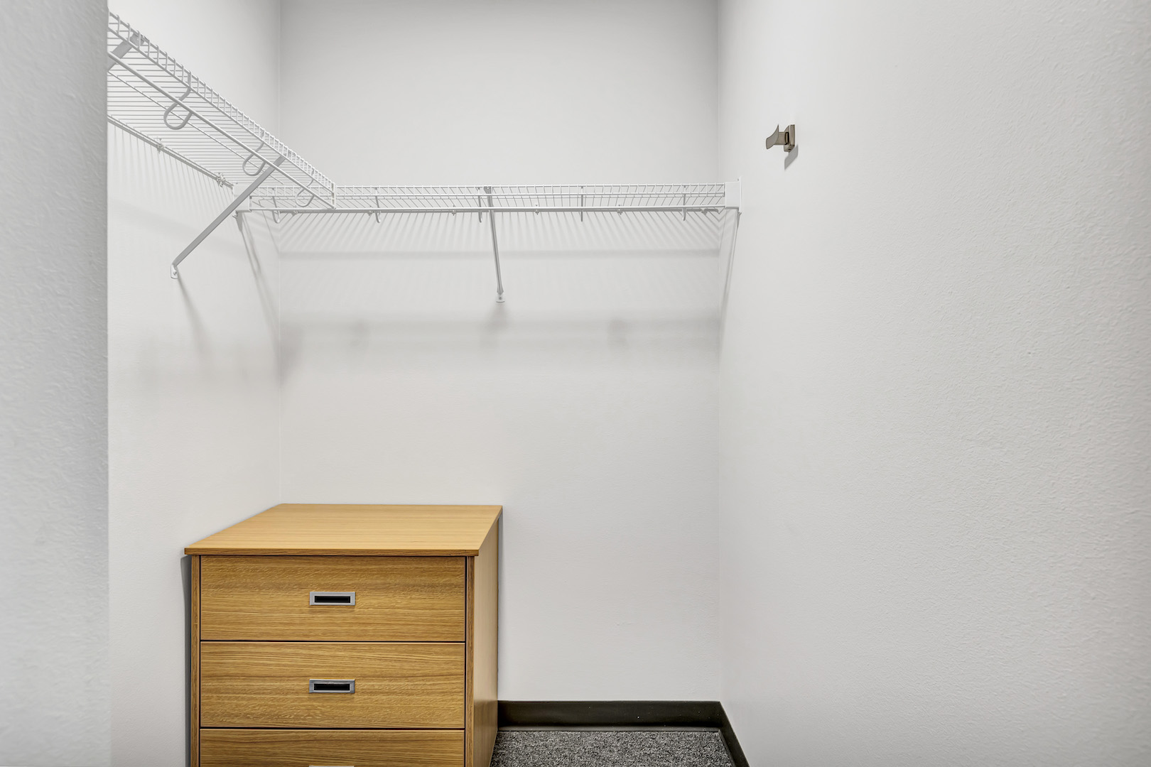 Walk-in closet with wire shelving and small dresser.