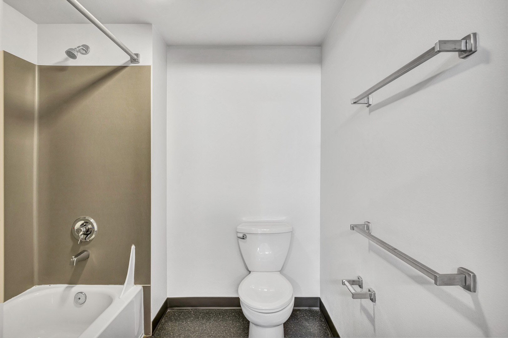 Bathroom showing bathtub, toilet, and towel bars from a different angle.