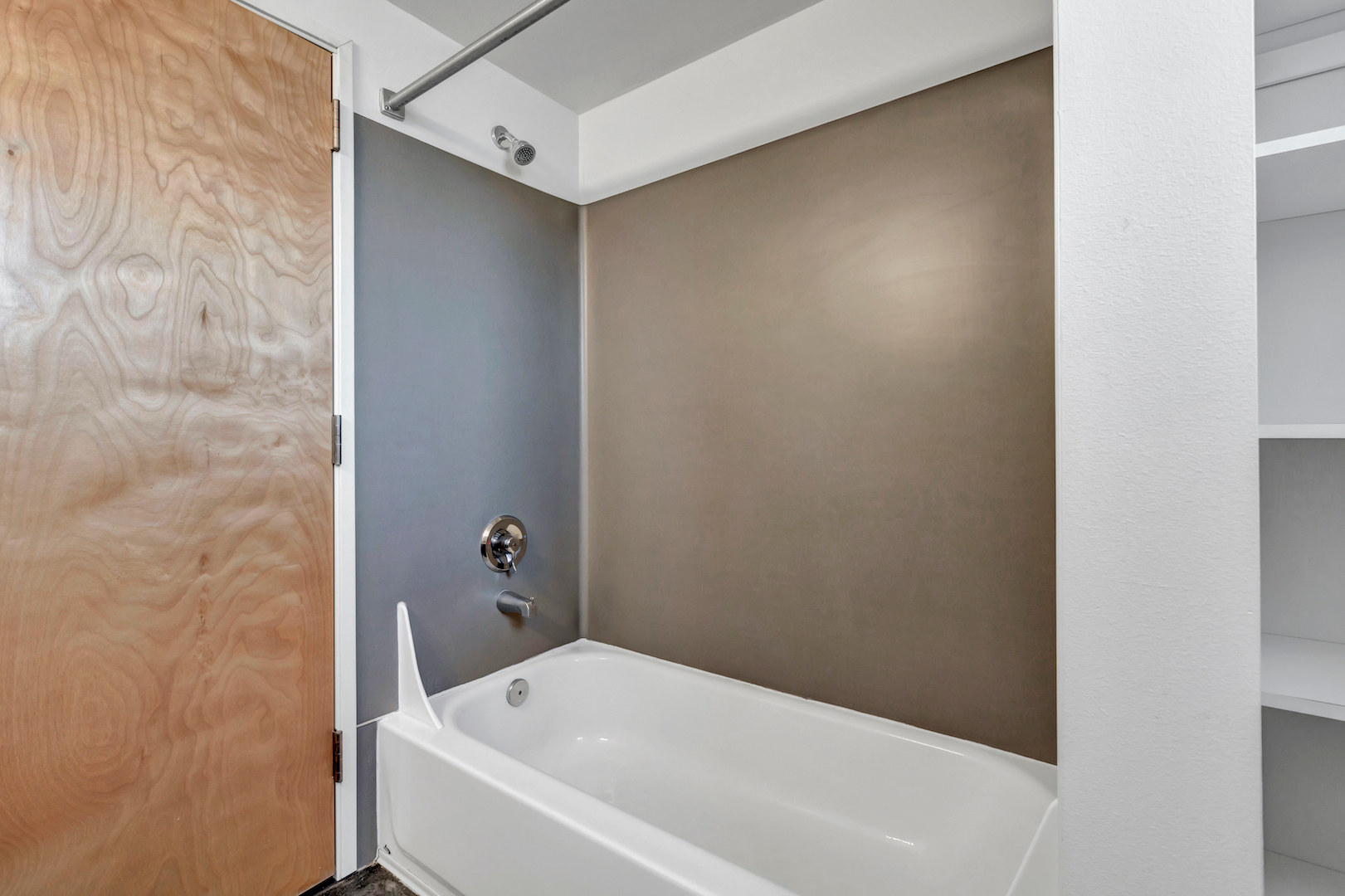 a photo showing a wall mounted shower with a bathtub.
