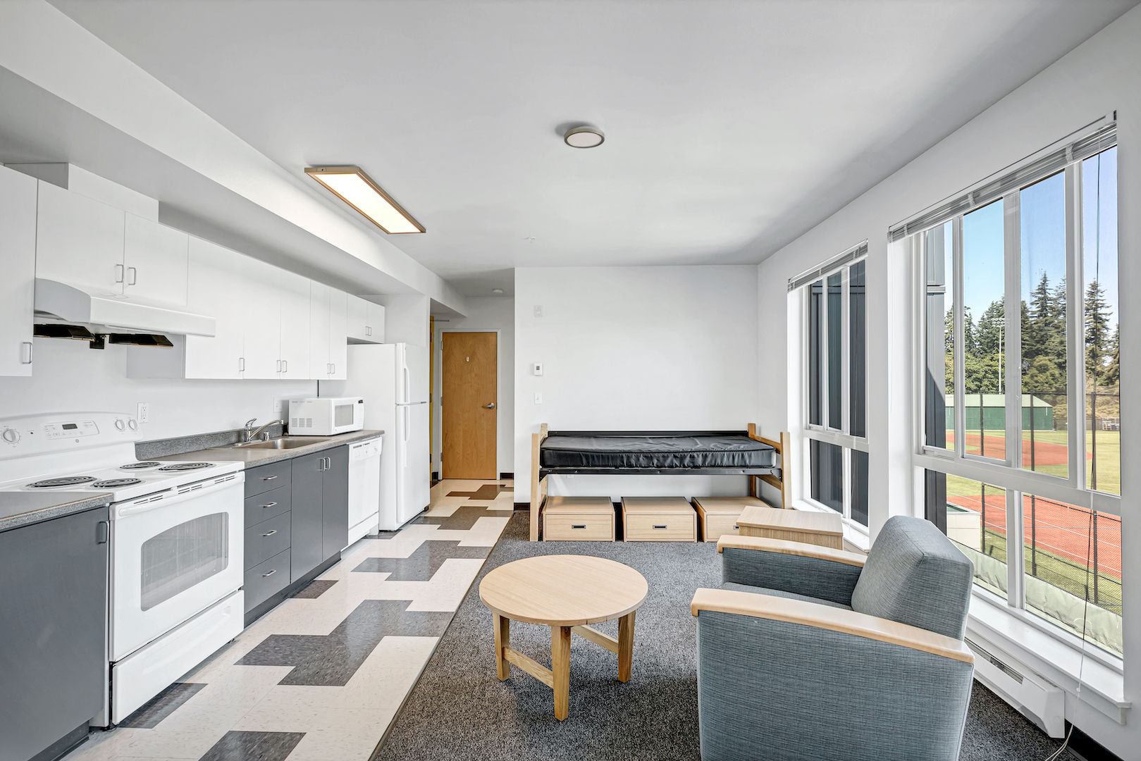 Another angle showing the living area of the studio unit in rainier place. Showcasing the large windows, kitchen, and furniture
