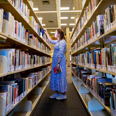 student looking at books in the library