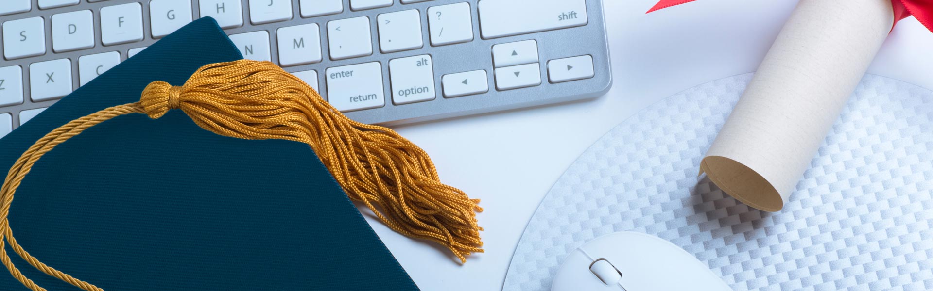 Graduation hat and diploma next to a keyboard